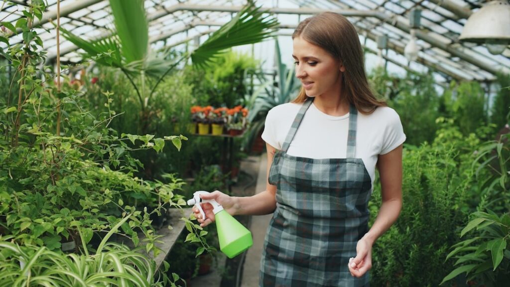 A young woman is watering in her organic home garden vegetable plants.